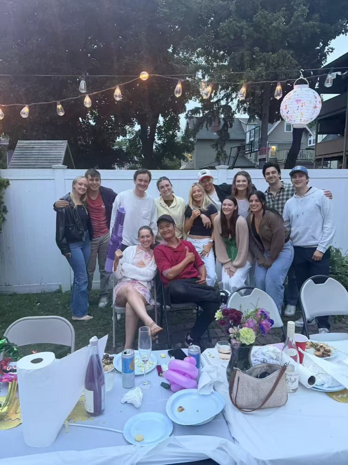 Under the Lights Friends gathered at a backyard hibachi party under string lights in CT